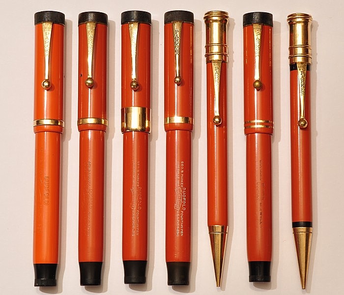 Parker Duofold &quot;Big Red&quot;. Von links: recht fühes Exemplar aus (hellerem) Hartgummi (1923), dunkleres Hartgummi (1924 - 25), &quot;De Luxe&quot; aus Zelluloid (1925), Zelluloid mit breitem Kappenband (1926 - 27), zugehöriger Bleistift, letzte Version der &quot;Flat Tops&quot; mit zwei Kappenbändern (1928) mit Bleistift.